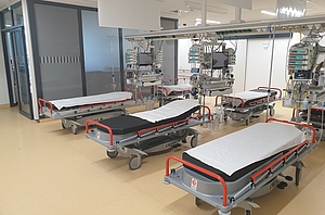 Mehrere Krankenliegen mit Überwachungsmonitoren in einem offenen Raum
