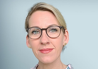 Porträt Frau mit dunkler Brille und blonden zusammengebundenen Haaren