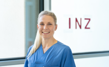 Frau mit zurückgesteckten Haaren vor Glasscheibe