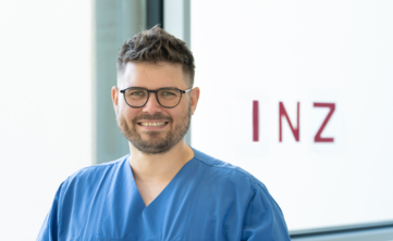 Mann mit Brill und kurzem Bart vor hellem Hintergrund