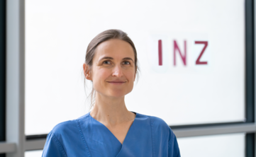 Frau mit dunklen Haaren vor Glasfront