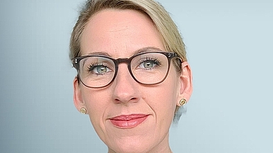 Porträt Frau mit dunkler Brille und blonden zusammengebundenen Haaren